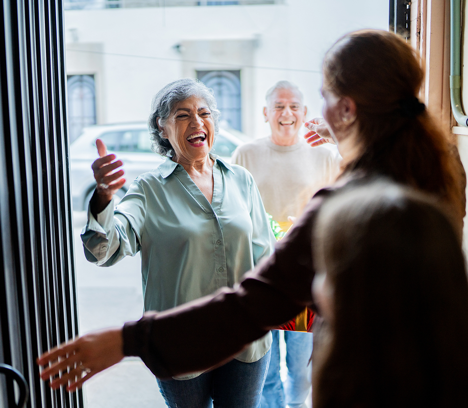 Woman greeting happy family at an open door
